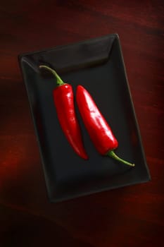 Still life. 2 chillies on a black