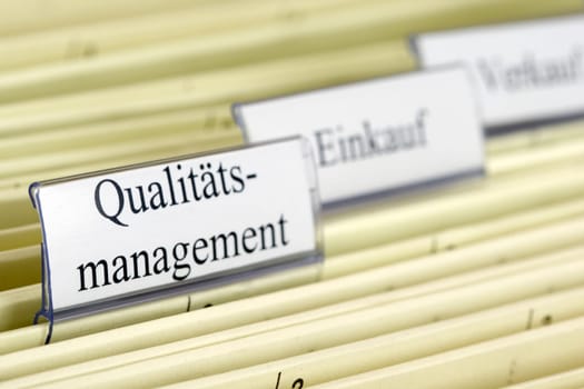 Close-up hanging files with tab "Qualitatsmanagement"" what means ""Quality Management"" in German"