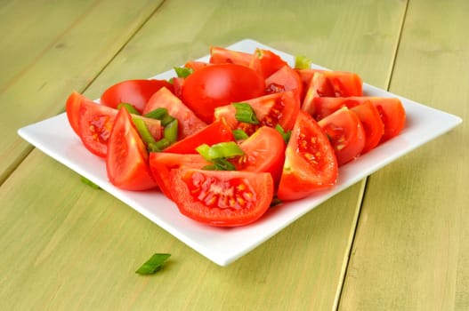 tomatos with green onions on a plate
