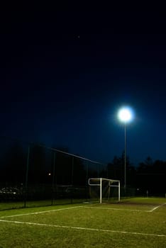 football field lit at night with goal and spot