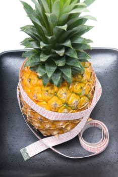 pineapple on a black plate with tape meter isolated on white background