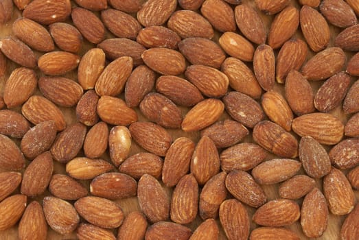 A macro of many almonds on a piece of wood.