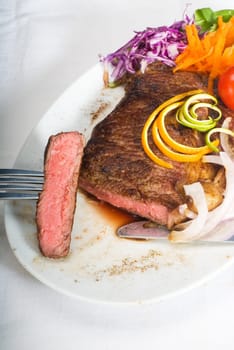 fresh juicy beef ribeye steak sliced ,with lemon and orange peel on top  and vegetable beside