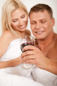 Young couple toasting champagne in bed