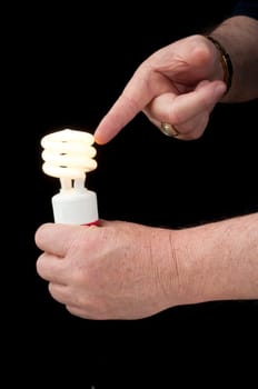Man holding a pigtail flourescent light bulb which is alight in one hand and pointing at it with the other hand suggesting this is the future