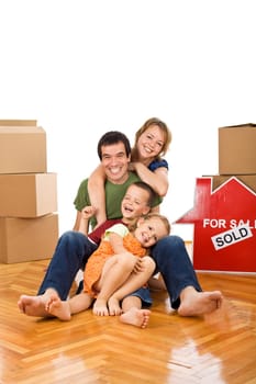 Happy couple with two kids having fun on the floor in their newly bought home - isolated