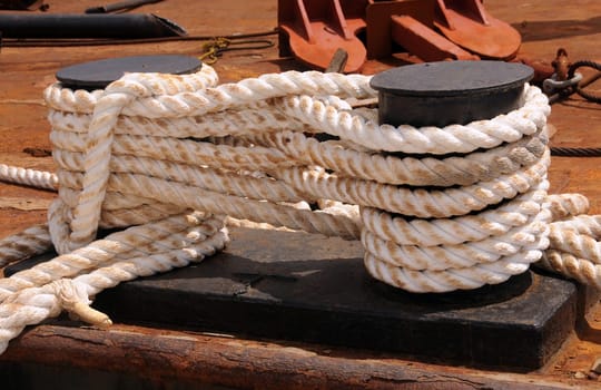 Thick white ropes used to tie down industrial ship