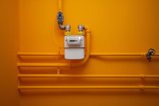 Pipes and gas-meter on orange wall