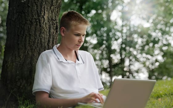 Young man using laptop in a park