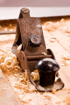 Old plane on wooden table with shavings