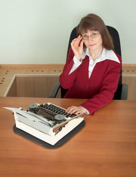 The young girl in office armchair with typewriter