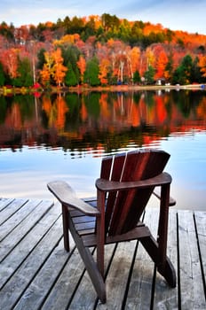 Wooden dock with chair on calm fall lake