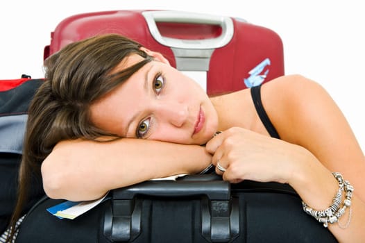 Young woman, resting her head on a suitcase, weary from travelling