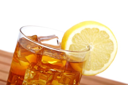 A glass of ice tea with lemon slice on wooden background. Shallow depth of field