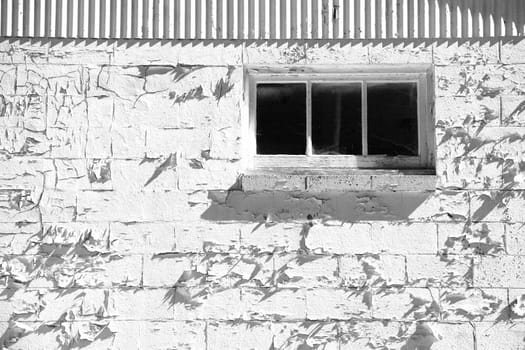 A window with peeling paint on the wall in black and white