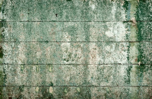 Green messy surface of the old, semidecayed wall covered with boards