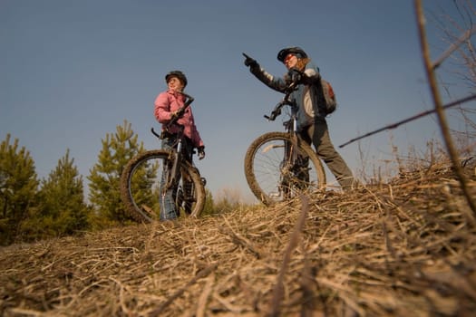 Two women-bikers standing. Shot from below