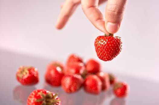 Hand picking a strawberry from a group.