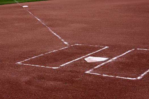 A close-up of the batters boxes and home plate on a vacant baseball diamond.
