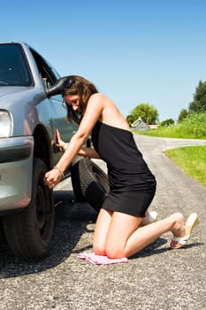 Young woman tightening the wheel nuts on a small rural road