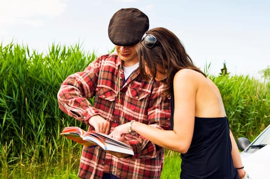 Young woman asking a farmer for advice on where to go, consulting a guide book