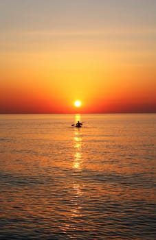 A man doing kayak at the sunrise on a calm sea