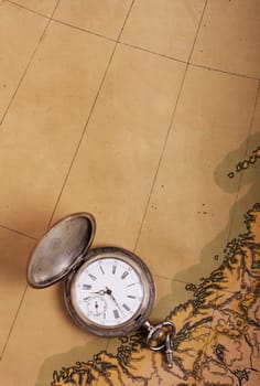 Old silver pocket watch on ancient map