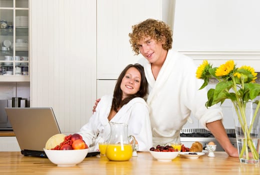Young couple at breakfast, wearing bathrobes in a kitchen and looking at the camera