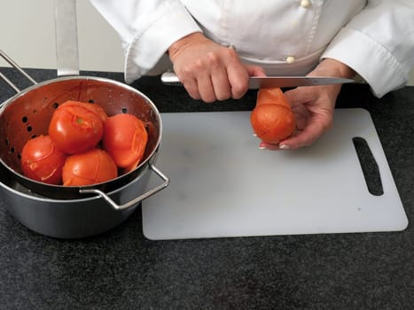 Chef is peeling bolied tomatos