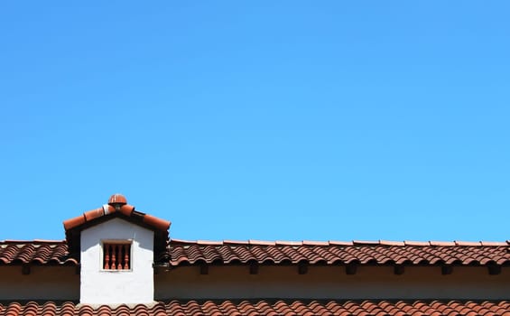 Roof top with small window and a blue sky in the background
