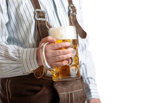 Bavarian man dressed with original leather trousers holds an Oktoberfest beer stein into the camera
