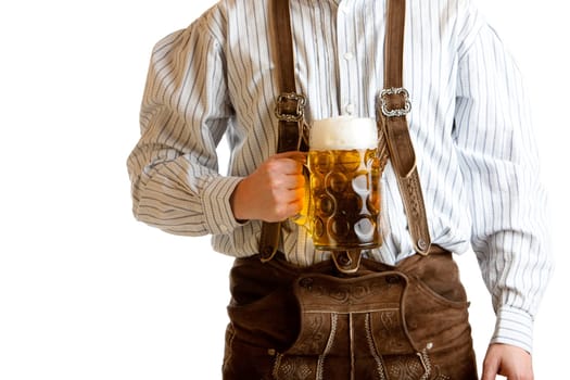 Bavarian man dressed with original leather trousers holds an Oktoberfest beer stein into the camera