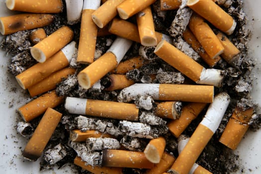 Ashtray full of burnt cigarettes. Dirty tobacco texture pattern