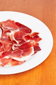 Slices of tasty spanish ham on white dish. Shallow depth of field