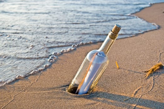 Message in bottle stuck in beach sand.