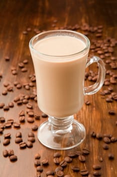 Arabica espresso beans around a glass mug of caffe latte.