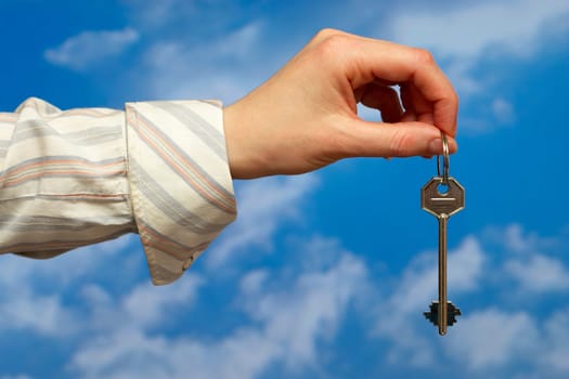 Hand holding a key over sky and clouds backgound