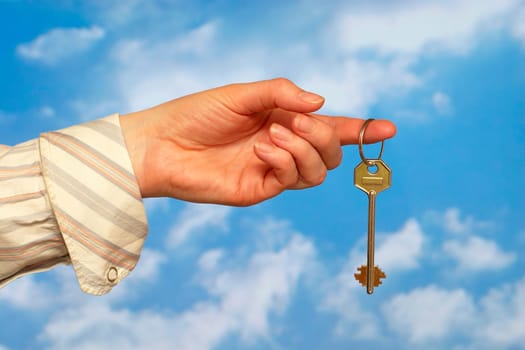 Hand holding a key over sky and clouds backgound