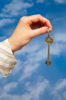 Hand holding a key over sky and clouds backgound