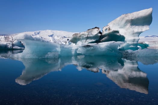 A glacial iceberg and its symmetrical reflection floating on the Iceberg Lagoon, Jokullsarlon, Iceland