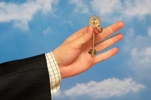 Hand holding a key over sky and clouds backgound