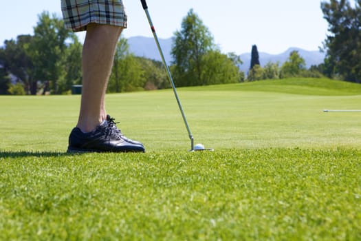 A Man golfing swinging his club toward the tee