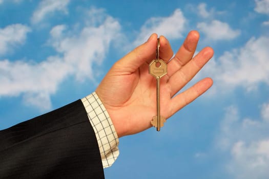 Hand holding a key over sky and clouds backgound