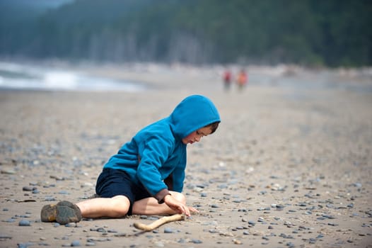 young boy in blue jacket on rocky beach