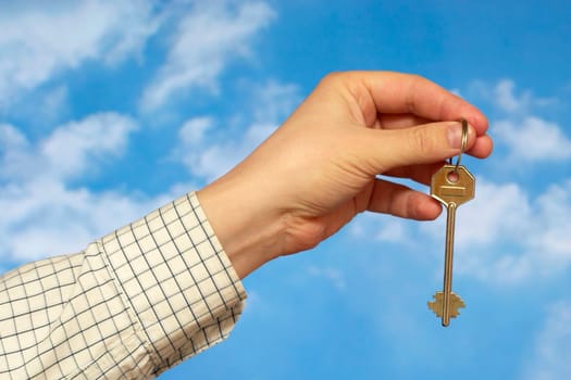 Hand holding a key over sky and clouds backgound
