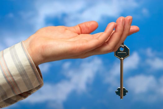Hand holding a key over sky and clouds backgound