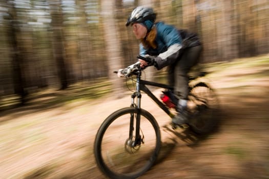 Woman-biker blurred in motion. Cross-country.