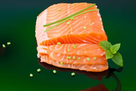 a piece of fresh raw salmon with basil leaves