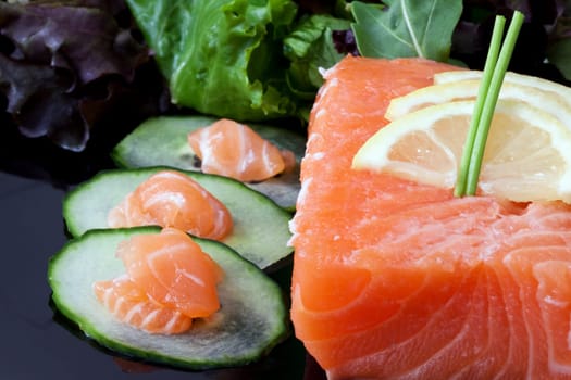 a piece of fresh raw salmon with basil leaves and salad