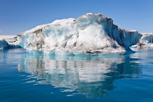 A glacial iceberg and its symmetrical reflection floating on the Iceberg Lagoon, Jokulsarlon, Iceland